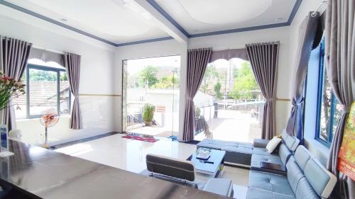 a living room with a blue couch and a large window at Hotel Mỹ Vy in Tánh Linh
