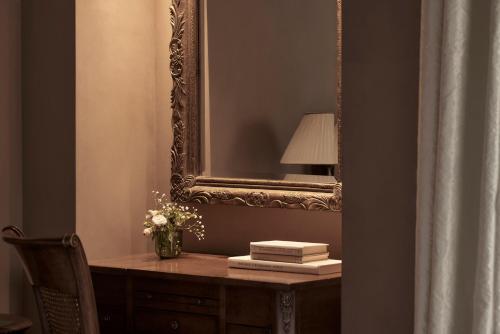 a mirror and a desk with a lamp and a vase of flowers at Hotel Ippoliti in Nafplio