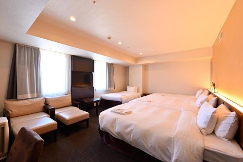 a hotel room with a large bed and a chair at Hotel Keihan Sapporo in Sapporo