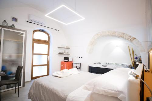 Ostuni Luxury Room في أوستوني: غرفة نوم بيضاء مع سرير وموقد