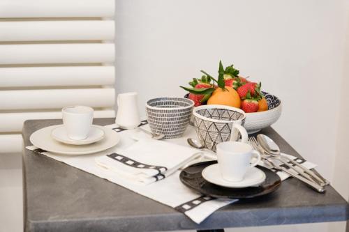 a table with plates and cups and a bowl of fruit at Ostuni Luxury Room in Ostuni
