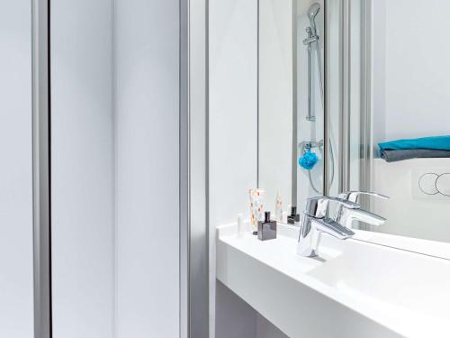W łazience znajduje się umywalka i lustro. w obiekcie hotelF1 Montpellier Sud w mieście Lattes