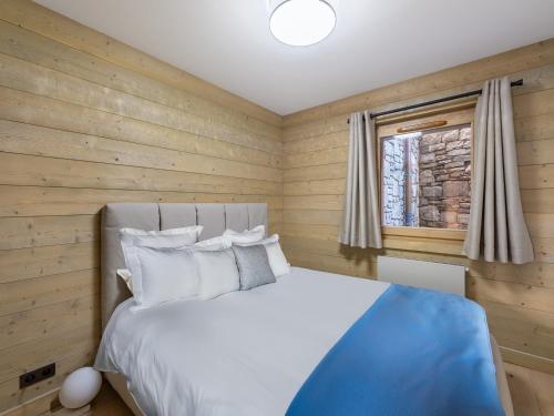 une chambre avec un lit avec des murs en bois et une fenêtre dans l'établissement Appartement moderne avec cheminée et terrasse - Près des pistes et commerces - FR-1-565-63, à Les Allues