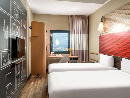 a hotel room with two beds and a window at Ibis Istanbul Tuzla Hotel in Tuzla