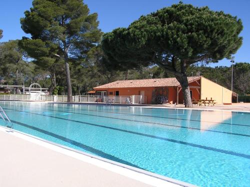 una piscina con un árbol y un edificio en superbe mobil home, climatisé, ss vis a vis, au calme, dans super domaine, en Fréjus