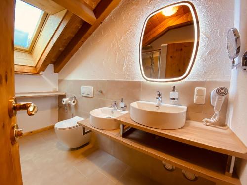 ein Badezimmer mit zwei Waschbecken, einem Spiegel und einem WC in der Unterkunft Urlaubshof Bechteler in Waltenhofen