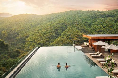 zwei Männer im Infinity-Pool in einem Resort in den Bergen in der Unterkunft Hyatt Regency Dehradun Resort and Spa in Dehradun