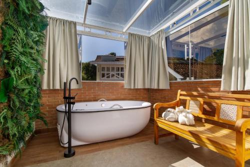 baño con bañera blanca y ventana en Casa Sabor Chocolate, en Campos do Jordão