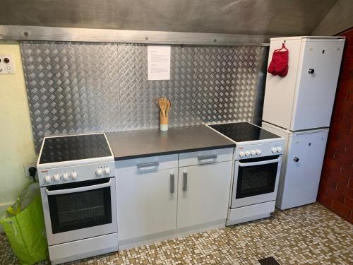 a kitchen with white appliances and a refrigerator at Hotel Schönbrunnen in Münchenbuchsee