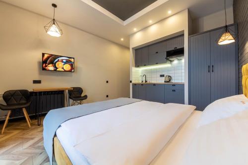 a bedroom with a large white bed and a kitchen at Idea Design Apart-Hotel Prorizna in Kyiv