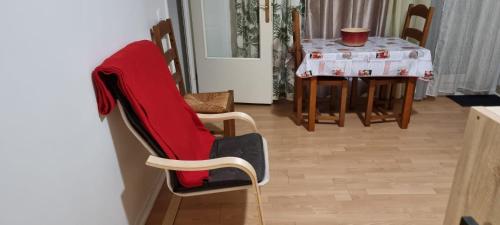 a dining room with a table and a red chair at KIEVAILLE in Plaisir