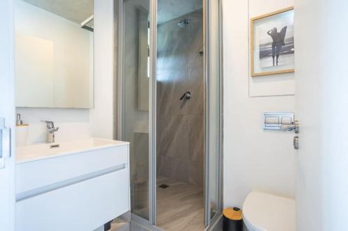 uma casa de banho com um chuveiro, um WC e um lavatório. em Modern Ground Floor Studio Apartment em Umhlanga