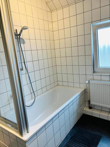 a bath tub in a tiled bathroom with a window at Shadow Sleep 2.0 in Schonungen