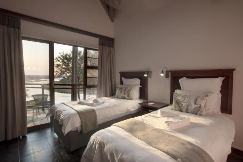 ein Hotelzimmer mit zwei Betten und Balkon in der Unterkunft Hippo Hills Lodge Ngwenya in Marloth Park