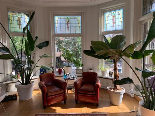 a living room with two chairs and potted plants at Stylish 3-bdrm apt. w/ terraces next to the beach in The Hague