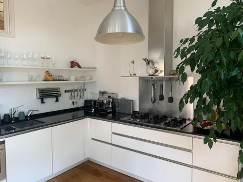 a kitchen with white cabinets and a stove top oven at Stylish 3-bdrm apt. w/ terraces next to the beach in The Hague
