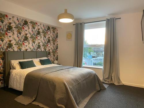 a bedroom with a bed with a large window at Modern studio apartment; 10min walk to town & quay in Exeter
