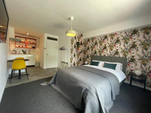 a bedroom with a large bed with floral wallpaper at Modern studio apartment; 10min walk to town & quay in Exeter