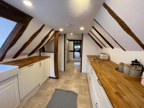 una cocina con armarios blancos y encimeras de madera en Rural Country Suites - Judge's Lodge, en East Grinstead
