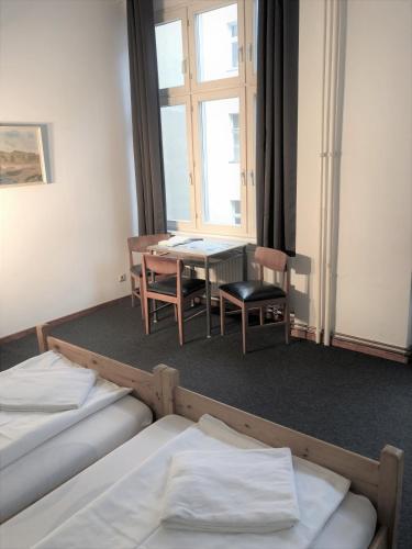 a room with two beds and a table and a window at Die Fabrik - Hostel in Berlin