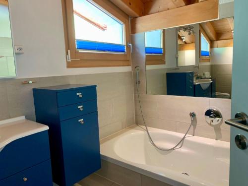 a bathroom with a bath tub and a sink at Pool Villa Savognin in Tinzen