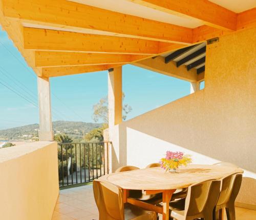 y balcón con mesa y sillas de madera. en Residence Maïna, en Cargèse