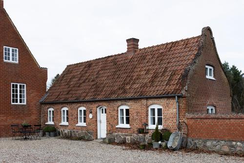 a brick house with white windows and a roof at Gartnerhuset på Kollerup in Hadsten Stationsby