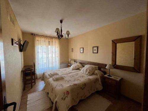 een slaapkamer met een groot bed en een spiegel bij El Sobrao de Gredos in Navarredonda de Gredos