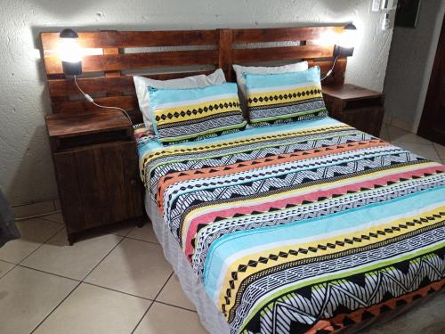 a bed with a wooden headboard and pillows on it at Bellamia in Marloth Park