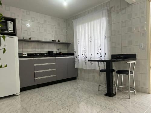 a kitchen with a table and a refrigerator at Apartamento Studio com banheiro privativo in São José