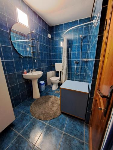 a blue tiled bathroom with a toilet and a sink at Apartament in Corbu in casa de vacanta in Corbu