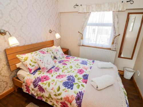 um quarto com uma cama com colcha floral e uma janela em The Orangery em Worcester