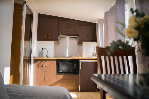 a kitchen with wooden cabinets and a table with a chair at Hostal Goyesco Plaza in Plasencia