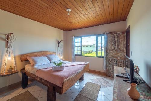 a bedroom with a bed and a large window at Praia Itápiruba 600m - WI-FI 800Mg - 1,5km BR 101 - Espaço comp - Varanda c Pôr do sol in Imbituba