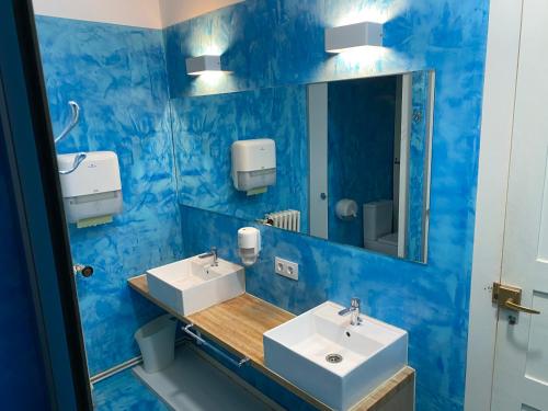 Baño azul con 2 lavabos y espejo en Albergue O Santo, en Arzúa