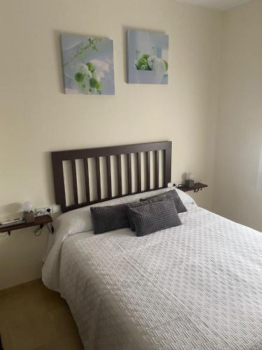 ein Bett in einem Schlafzimmer mit zwei Bildern an der Wand in der Unterkunft APARTAMENTO TURÍSTICO VEGA HOUSE in Córdoba