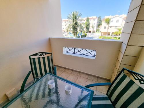een balkon met een glazen tafel en 2 stoelen bij Yaar Apartment with pool, tennis court and Bathroom with Bathtub in Pyla