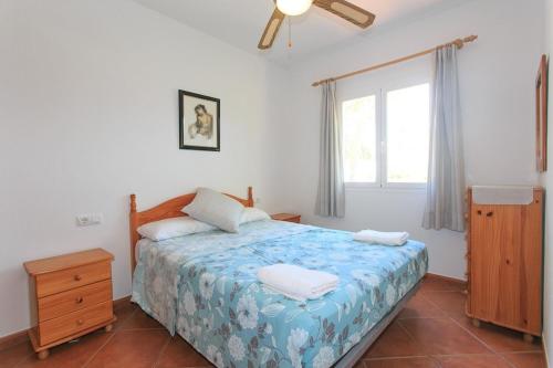 a bedroom with a bed with a blue comforter and a window at Villa Toymi in Ciutadella