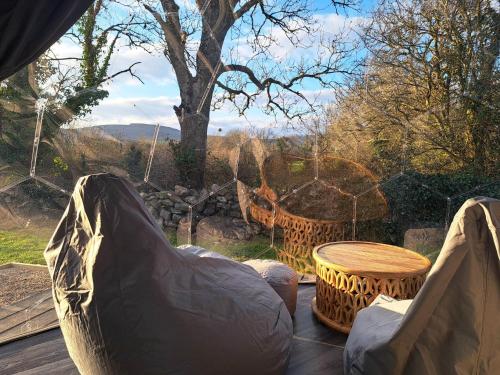 a hammock on a deck with a table and a tree at Luxury Glamping Dome with views of the Burren in Boston