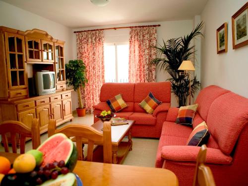 a living room with a red couch and a table at Apartamentos Miguel Angel in Estepona
