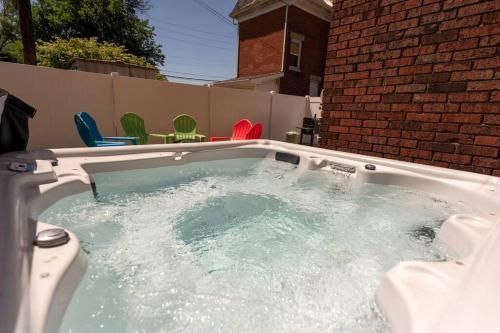 a hot tub in a backyard with colorful chairs at Downtown Retreat, Hot Tub, Firepit, Grill in Michigan City