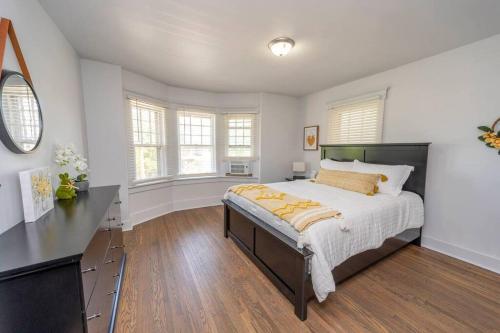 a bedroom with a bed and a desk and windows at Downtown Retreat, Hot Tub, Firepit, Grill in Michigan City