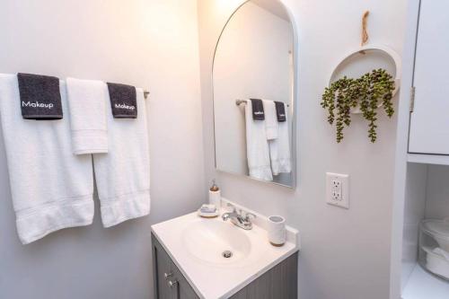 a white bathroom with a sink and a mirror at Downtown Retreat, Hot Tub, Firepit, Grill in Michigan City