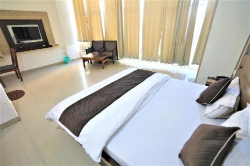 a bedroom with a large white bed and a chair at Mahadev Hotel and Resorts in Katra