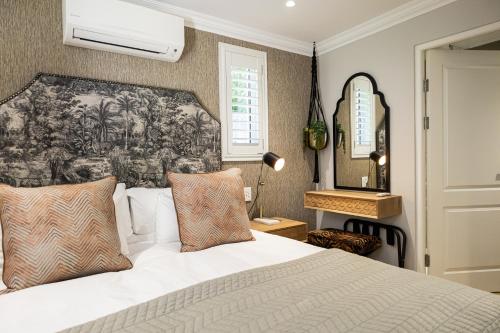um quarto com uma cama branca e uma grande cabeceira de cama. em Cape Village Lodge em Durbanville