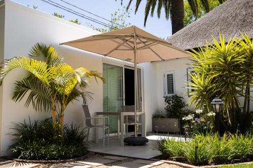 a house with a table and an umbrella at Cape Village Lodge in Durbanville