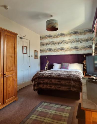 a bedroom with a large bed and a tv at Langass Lodge in Carinish