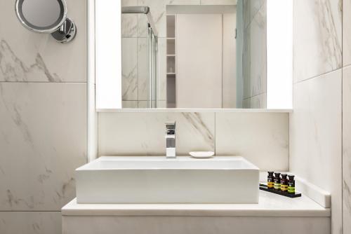 a white bathroom with a sink and a mirror at TRYP by Wyndham Corfu Dassia in Dassia