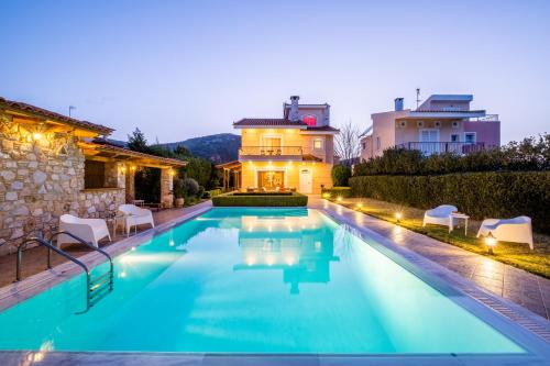 a swimming pool in front of a house at Phoceus Poolfront Grande Villa in Palaiá Fókaia