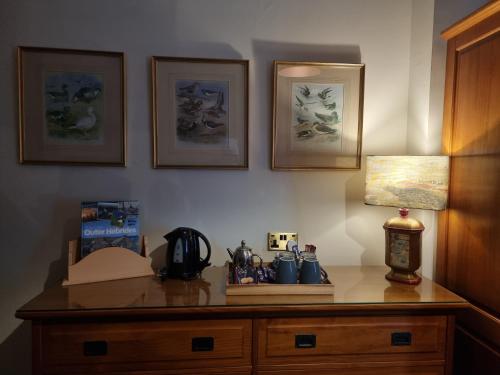 a desk with a lamp on top of it with pictures at Langass Lodge in Carinish